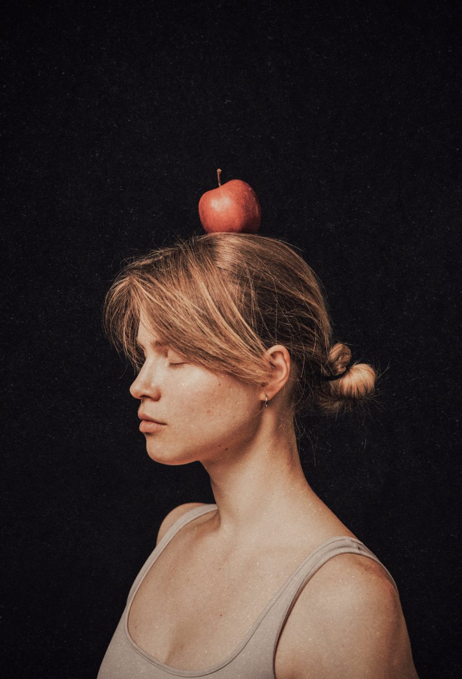 Margo with an apple balanced on her head, eyes closed